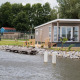 Moderne Waterlodge type 1 ved søbred med terrasse og udsigt over vandet, omgivet af natur og træer.