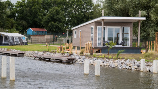 Waterlodge moderne type 1 au bord de l’eau, terrasse avec sièges, vue sur l’eau et nature environnante.