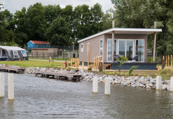 Moderne Waterlodge type 1 ved søbred med terrasse og udsigt over vandet, omgivet af natur og træer.
