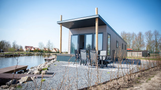 Waterlodge tipo 1 junto al lago, diseño moderno, área exterior con sillas y entorno natural sereno.