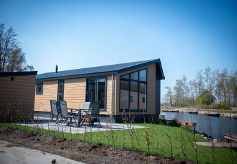 Moderne Waterlodge type 2 med stor vinduesfacade, terrasse og udsigt over vand i solrigt landskab