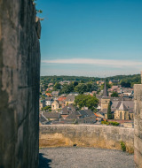 Blick von einer Steinmauer auf eine Stadtlandschaft in einem Glamping-Ferienpark bei sonnigem Wetter.