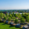 Aerial view of a holiday park featuring glamping lodges, surrounded by green trees and open countryside.