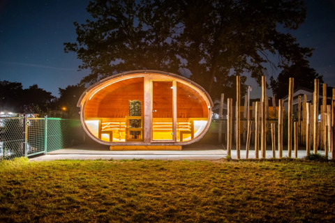 Illuminated glamping pod at night in a holiday park, showcasing modern, cozy accommodations outdoors.