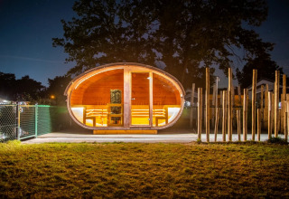 Oplyst glampinghytte om natten på en ferielejrplads med moderne faciliteter og hyggelig stemning.