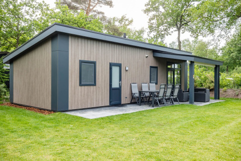 Moderna Forest Lodge DeLuxe con fachada de madera y terraza en Kampeerdorp de Zandstuve, Países Bajos.