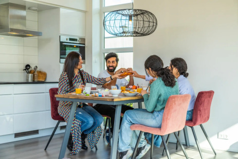 Familia desayunando junta en la mesa de una cocina moderna en un alojamiento glamping en un parque vacacional.