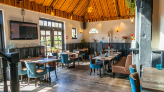 Acogedor restaurante en un parque vacacional con techo de madera, muebles modernos y clima soleado.