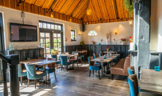 Acogedor restaurante en un parque vacacional con techo de madera, muebles modernos y clima soleado.