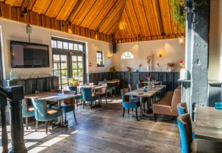 Gezellige, lichte eetruimte in een vakantiepark met houten dak, moderne meubels en veel daglicht.