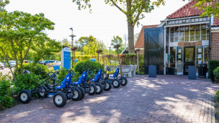 Foto de un parque vacacional con glamping, karts estacionados frente al vestíbulo y vegetación.