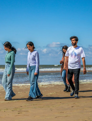 Cuatro personas caminan por la playa en un día soleado en un parque vacacional con alojamiento glamping.