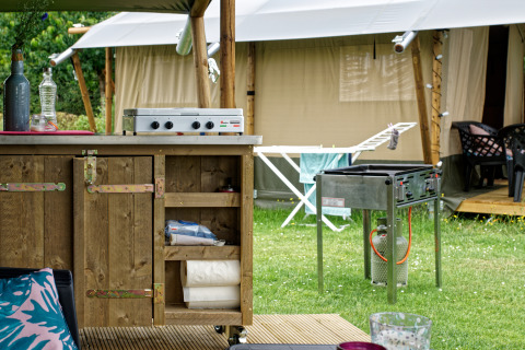 Area cucina all'aperto con barbecue e tenda safari al Camping La Dolce Vita nei Paesi Bassi.