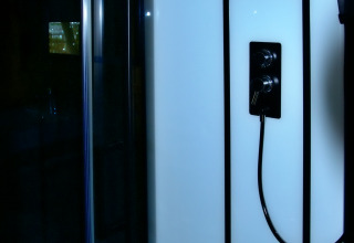 Moderne douche in safaritent bij Camping La Dolce Vita in Nederland met glazen panelen en zwarte armaturen.