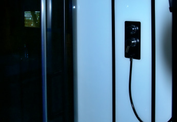 Douche moderne dans une tente safari à Camping La Dolce Vita aux Pays-Bas avec panneaux de verre noirs.