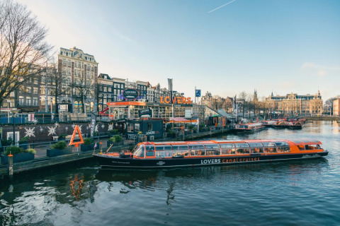 Vista panorámica de un barco de LOVERS canal cruises en Ámsterdam con decoraciones y edificios festivos.
