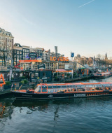 Scenic view of a LOVERS canal cruise boat docked in Amsterdam surrounded by festive city holiday decorations.