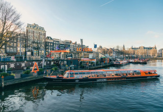 Scenic view of a LOVERS canal cruise boat docked in Amsterdam surrounded by festive city holiday decorations.