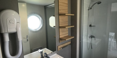 Baño moderno en Lodge XL de Vakantiepark Bergumermeer, Países Bajos, con ducha, lavabo y ventana redonda.