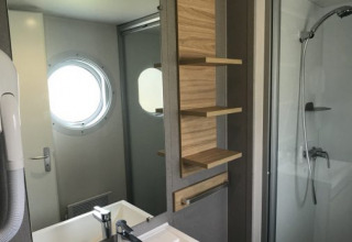 Moderne badeværelse i Lodge XL ved Vakantiepark Bergumermeer med bruser, håndvask og rundt vindue.