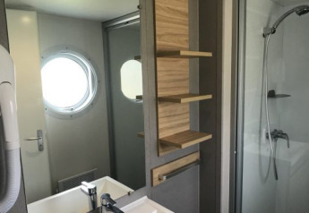 Modern bathroom in Lodge XL at Vakantiepark Bergumermeer, Netherlands, with shower, sink and porthole window.