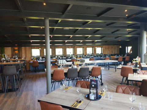 Zona de restaurante moderna y elegante en Vakantiepark Bergumermeer, con mesas y sillas de madera.