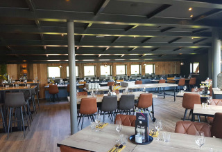 A stylish dining area at Vakantiepark Bergumermeer, featuring modern wooden tables, chairs, and glassware.