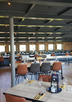 Zona de restaurante moderna y elegante en Vakantiepark Bergumermeer, con mesas y sillas de madera.