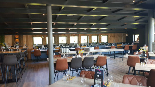 Zona de restaurante moderna y elegante en Vakantiepark Bergumermeer, con mesas y sillas de madera.