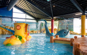 Indendørs børnepool med farverige legetøjsfigurer og vandeffekter i Vakantiepark Bergumermeer, Friesland.
