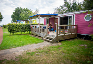 Famille profitant d’une terrasse devant un chalet coloré à Vakantiepark Bergumermeer, Frise, Pays-Bas.