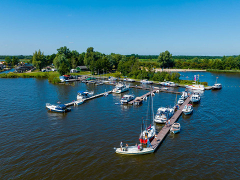 View of boats docked at the marina in Vakantiepark Bergumermeer, Friesland, Netherlands, on a sunny summer day.
