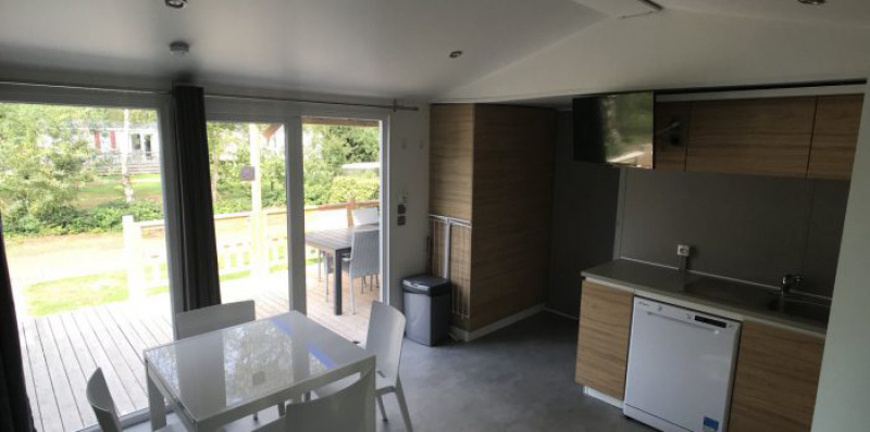 Interior del Lodge XL en Vakantiepark Bergumermeer, Países Bajos, con ventanales y cocina moderna.