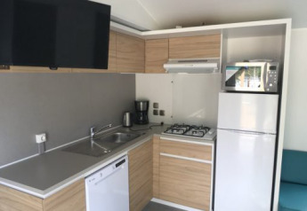 Modern Lodge XL kitchen at Vakantiepark Bergumermeer in the Netherlands with fridge, stove, and TV.