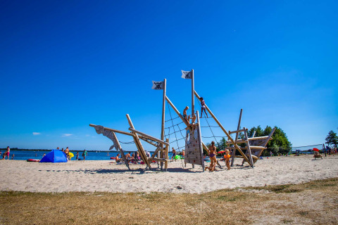 Kinder spielen an einem Piratenschiff-Spielplatz am Strand im Vakantiepark Bergumermeer, Friesland.