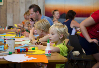 Children doing crafts at a table in Vakantiepark Bergumermeer holiday park, Friesland, Netherlands, with adults.