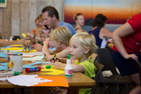 Kinderen knutselen samen met volwassenen aan een tafel in Vakantiepark Bergumermeer, Friesland, Nederland.