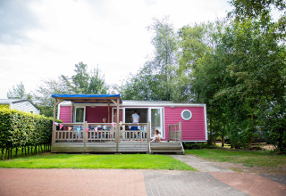 Pink holiday cabin with porch and children playing at Vakantiepark Bergumermeer in Friesland, Netherlands.