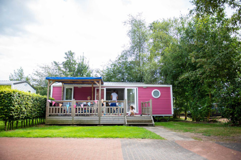 Roze chalet met veranda en spelende kinderen bij Vakantiepark Bergumermeer, Friesland, Nederland.