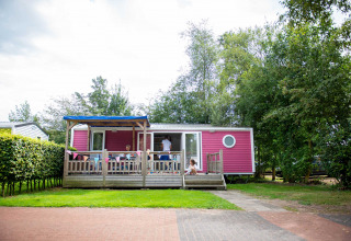 Cabaña rosa con porche y niños jugando en Vakantiepark Bergumermeer, Friesland, Países Bajos.