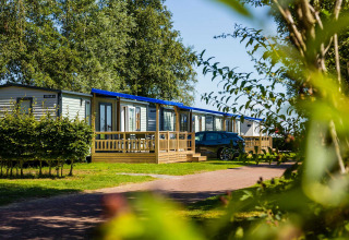Moderne Ferienhäuser mit Veranda und Autos im Vakantiepark Bergumermeer, Friesland, Niederlande, an einem sonnigen Tag.