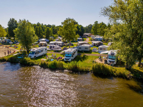 Autocaravanas y tiendas junto al lago en Vakantiepark Bergumermeer, parque vacacional en Frisia, Países Bajos.
