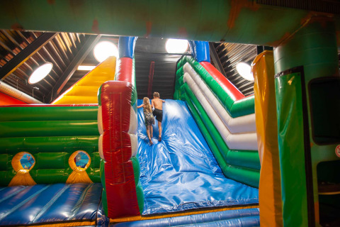 Dos niños juegan en un gran tobogán hinchable y colorido en la Vakantiepark Bergumermeer en Frisia.