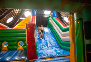 Zwei Kinder spielen auf einer großen, bunten Hüpfburg-Rutsche im Ferienpark Bergumermeer, Friesland.