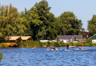 Feriepark Bergumermeer i Friesland, Holland, med familier på vandet, telte og grøn natur i baggrunden.