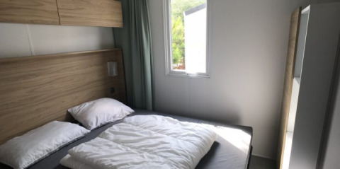 Dormitorio moderno con cama doble y gran ventana en Lodge XL de Vakantiepark Bergumermeer, Países Bajos.