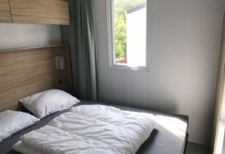 Dormitorio moderno con cama doble y gran ventana en Lodge XL de Vakantiepark Bergumermeer, Países Bajos.