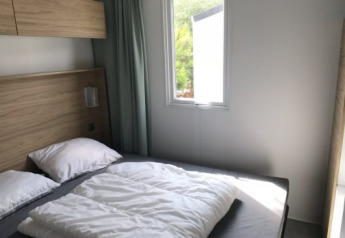 Modern bedroom with a double bed and large window in Lodge XL at Vakantiepark Bergumermeer, Netherlands.