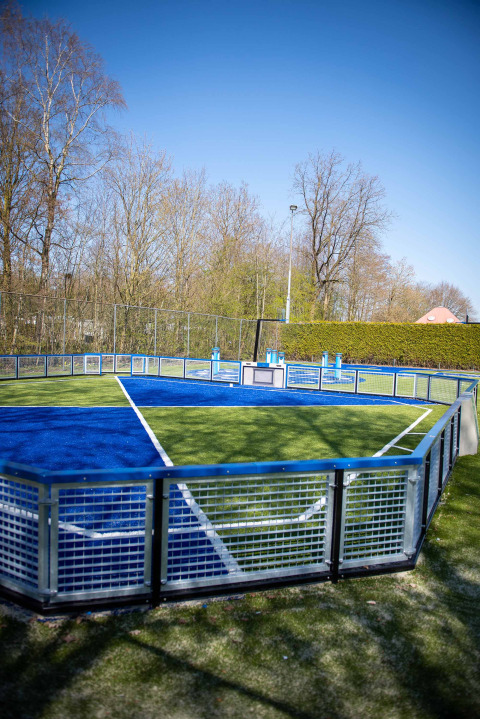 Moderner, umzäunter Sportplatz mit blau-grünem Feld im Vakantiepark Bergumermeer, Friesland, Niederlande.