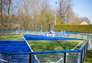 Moderner, umzäunter Sportplatz mit blau-grünem Feld im Vakantiepark Bergumermeer, Friesland, Niederlande.